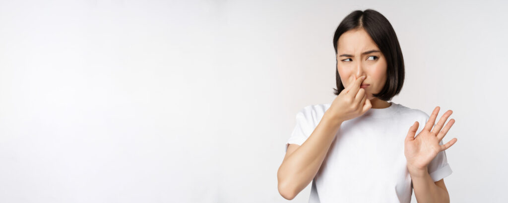 asian girl looks disgusted rejecting product with bad smell shut nose from aversion cringe standing against white background scaled 1