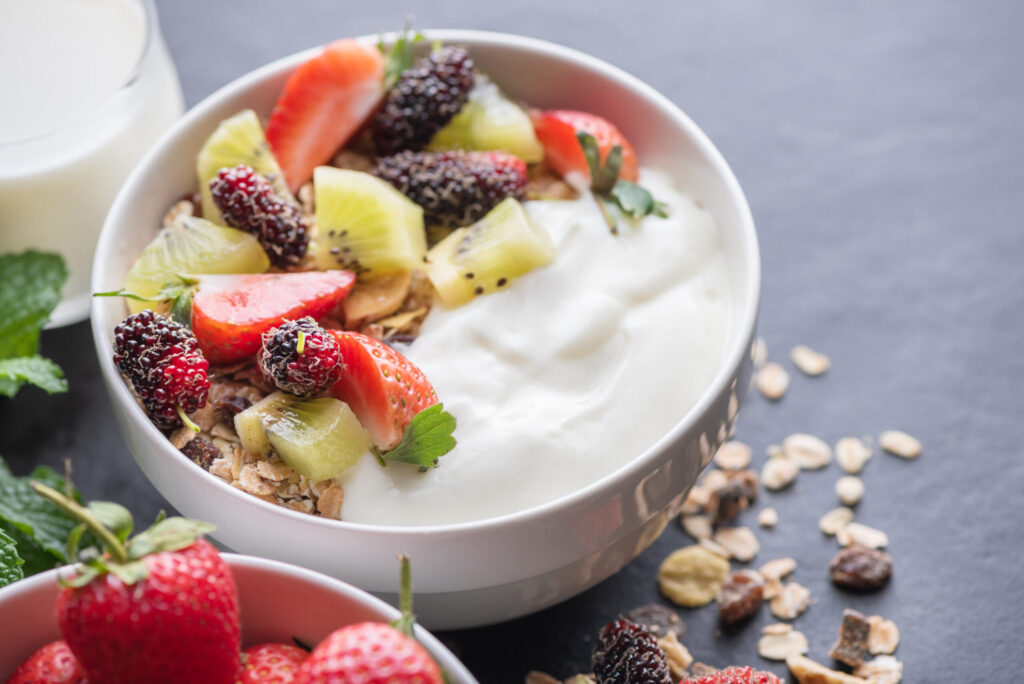 bowl oat granola with yogurt fresh mulberry strawberries kiwi mint nuts black rock board healthy breakfast copy space healthy breakfast menu concept scaled 1