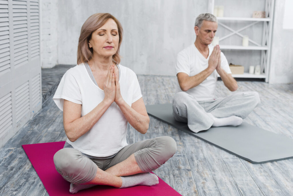 concentrated senior couple performing yoga home scaled 1