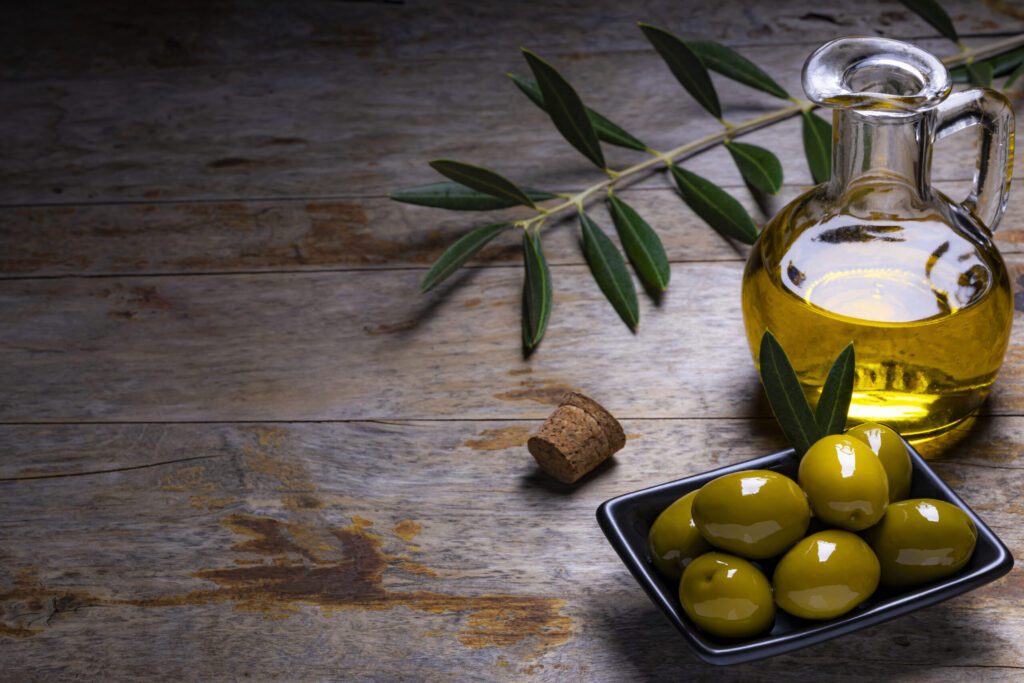 tasty looking olives extra virgin olive oil olive leafs dark wooden background scaled 1