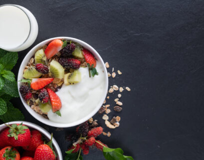 bowl oat granola with yogurt fresh mulberry strawberries kiwi mint nuts black rock board healthy breakfast top view copy space flat lay healthy breakfast menu concept scaled 1