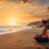 Woman doing yoga at beach – Padmasana lotus pose